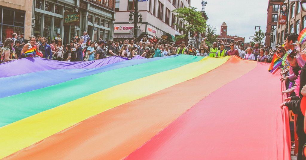 Un grup de manifestants agafa una gran bandera LGTBI durant la manifestació del 28 de juny (Mercedes Mehling / Unsplash)