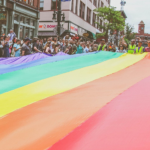 Un grup de manifestants agafa una gran bandera LGTBI durant la manifestació del 28 de juny (Mercedes Mehling / Unsplash)