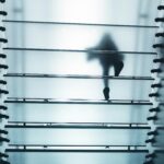 Una persona camina per una escala de cristall