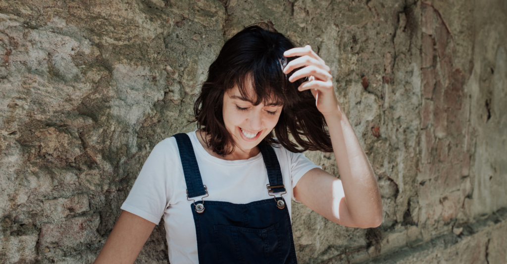 La dramaturga Clàudia Cedó somrient vestida amb una samarreta blanca i un mono de tirants blau (Escenaris Especials/Wikimedia Commons)